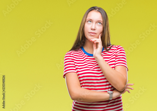 Young caucasian beautiful woman over isolated background with hand on chin thinking about question, pensive expression. Smiling with thoughtful face. Doubt concept.