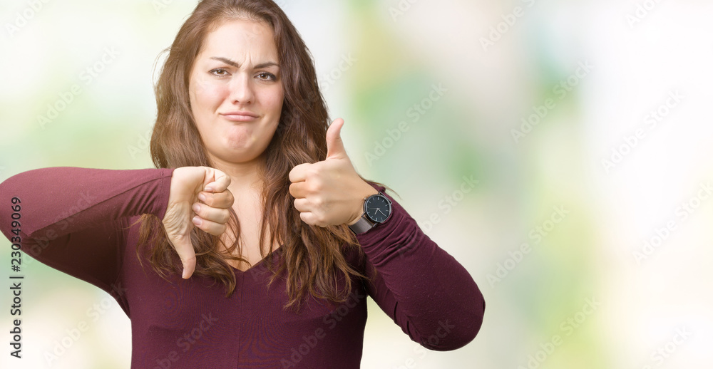 Beautiful and attractive plus size young woman wearing a dress over isolated background Doing thumbs up and down, disagreement and agreement expression. Crazy conflict Beautiful and attractive plus size young woman wearing a dress over isolated background Doing thumbs up and down, disagreement and agreement expression. Crazy conflict