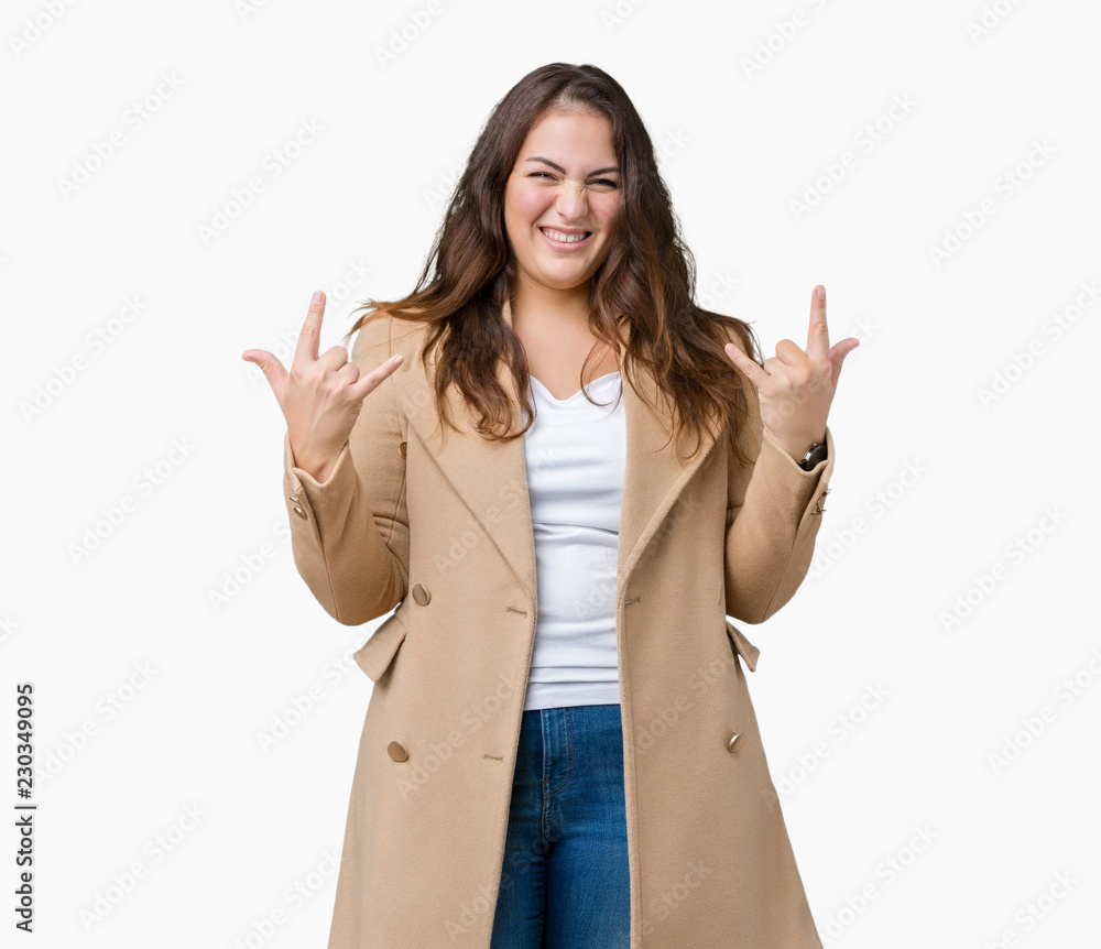 Beautiful plus size young woman wearing winter coat over isolated background shouting with crazy expression doing rock symbol with hands up. Music star. Heavy concept. Beautiful plus size young woman wearing winter coat over isolated background shouting with crazy expression doing rock symbol with hands up. Music star. Heavy concept.