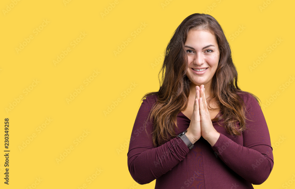 Beautiful and attractive plus size young woman wearing a dress over isolated background praying with hands together asking for forgiveness smiling confident. Beautiful and attractive plus size young woman wearing a dress over isolated background praying with hands together asking for forgiveness smiling confident.