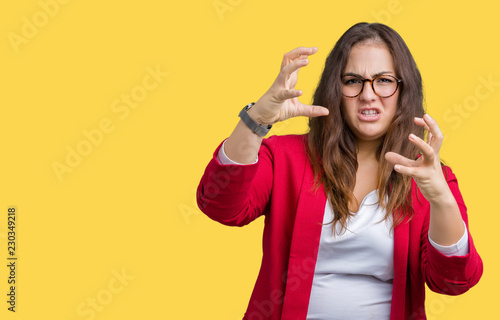 Beautiful plus size young business woman wearing elegant jacket and glasses over isolated background Shouting frustrated with rage, hands trying to strangle, yelling mad
