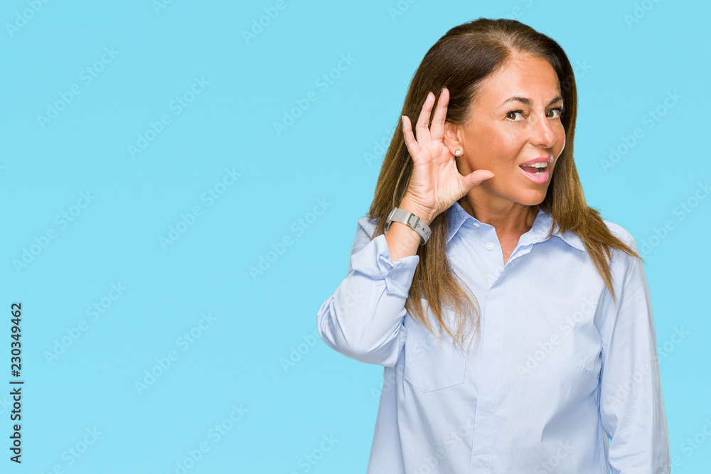 Beautiful middle age business adult woman over isolated background smiling with hand over ear listening an hearing to rumor or gossip. Deafness concept. Beautiful middle age business adult woman over isolated background smiling with hand over ear listening an hearing to rumor or gossip. Deafness concept.
