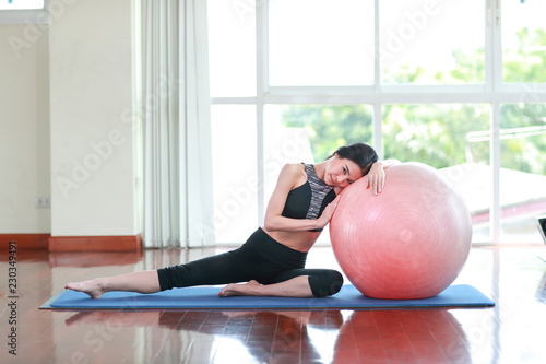 young healthy and sporty woman do yoga indoor with pink ball