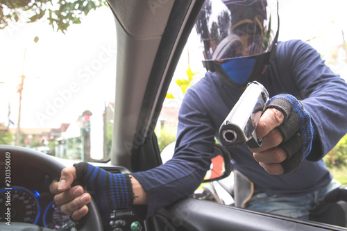Foto thief with gun on motorcycle trying to steal car or money (theft concept)