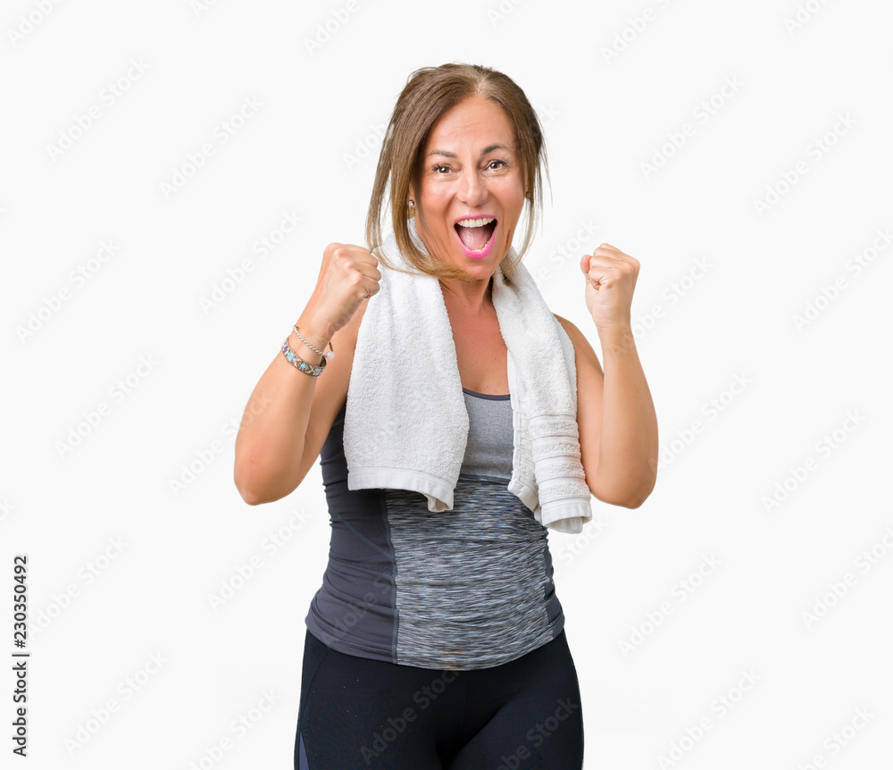 Beautiful middle age woman wearing sport clothes and a towel over isolated background very happy and excited doing winner gesture with arms raised, smiling and screaming for success Beautiful middle age woman wearing sport clothes and a towel over isolated background very happy and excited doing winner gesture with arms raised, smiling and screaming for success