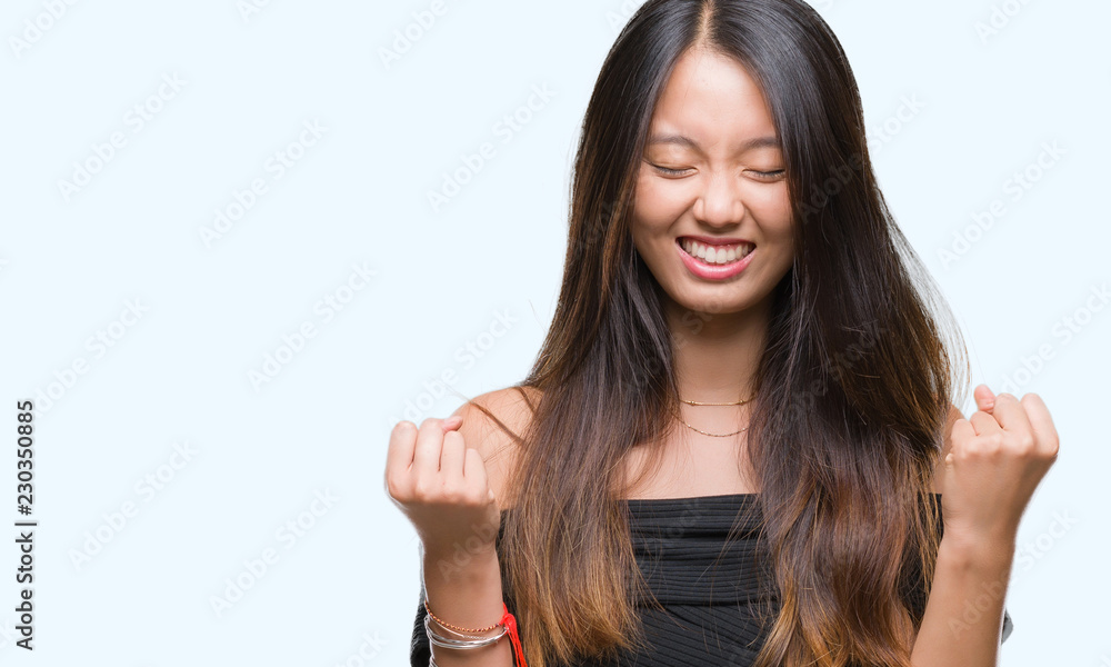 Young asian woman over isolated background very happy and excited doing winner gesture with arms raised, smiling and screaming for success. Celebration concept. Young asian woman over isolated background very happy and excited doing winner gesture with arms raised, smiling and screaming for success. Celebration concept.