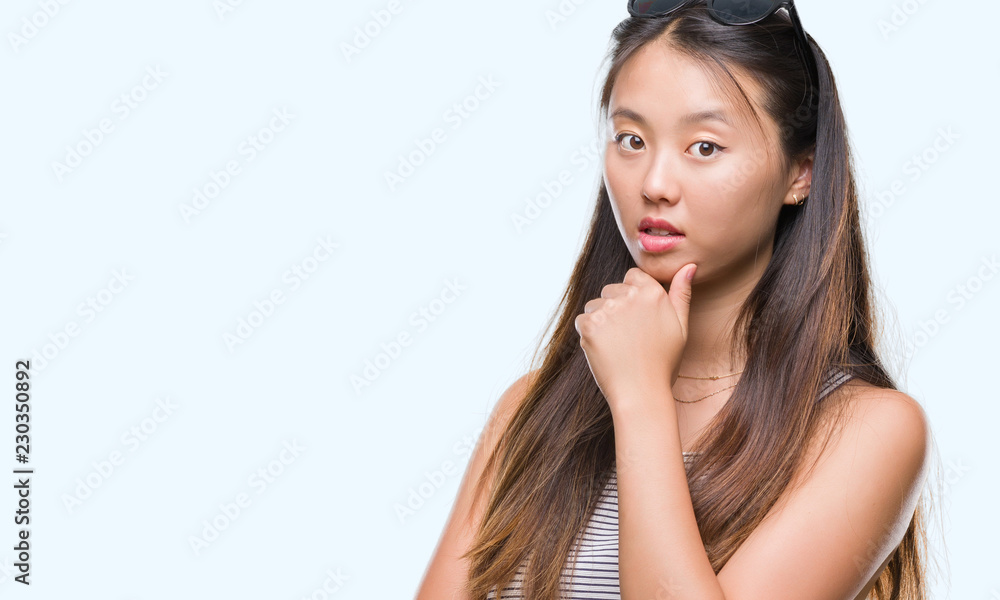 Young asian woman wearing sunglasses over isolated background looking confident at the camera with smile with crossed arms and hand raised on chin. Thinking positive. Young asian woman wearing sunglasses over isolated background looking confident at the camera with smile with crossed arms and hand raised on chin. Thinking positive.