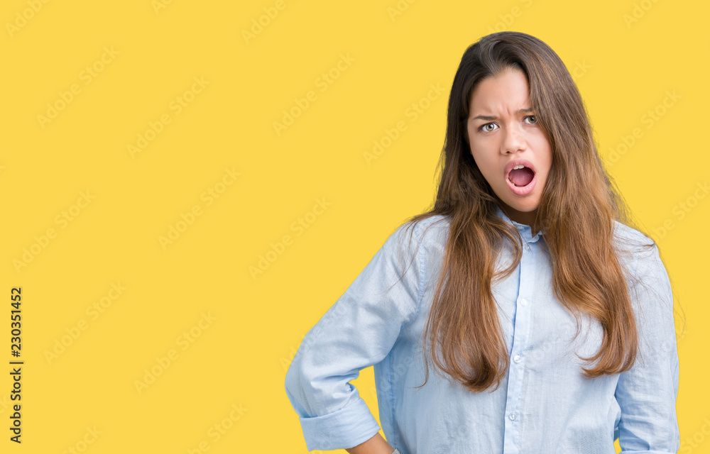 Young beautiful brunette business woman over isolated background In shock face, looking skeptical and sarcastic, surprised with open mouth