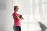 Young sporty woman doing yoga exercise near bright window