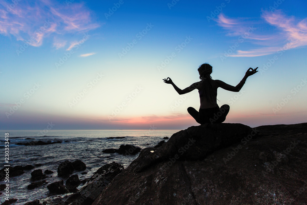 Yoga woman silhouette on the Sea during amazing sunset.