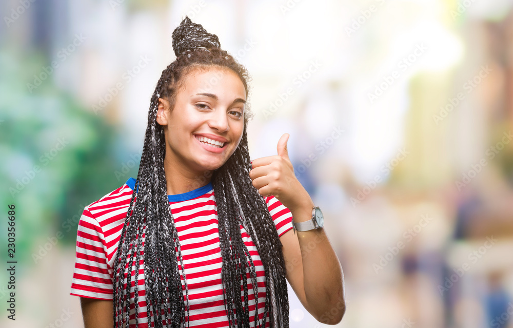 Young braided hair african american girl over isolated background doing happy thumbs up gesture with hand. Approving expression looking at the camera with showing success.