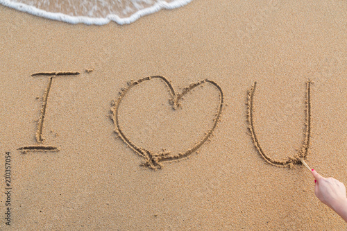 Message i love you on the sand with woman hand drawing