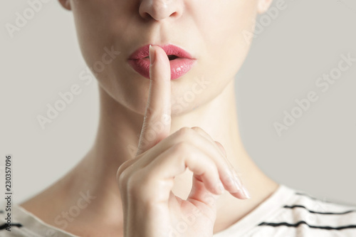 Finger on lips - silent gesture, Woman holding her finger to her lips in a gesture for silence. photo
