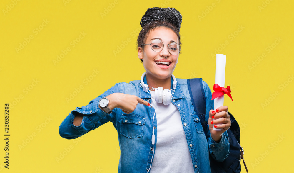 Young braided hair african american student girl holding degree over isolated background with surprise face pointing finger to himself