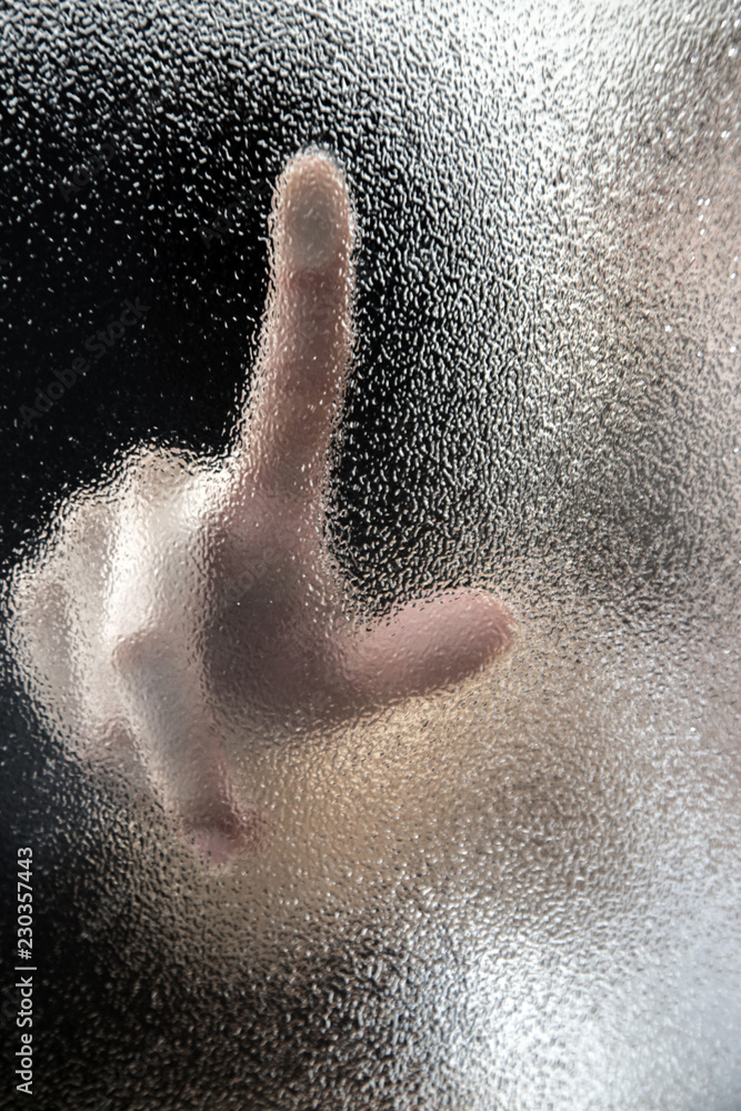 Finger touching the textured glass, blur and abstract style Finger touching the textured glass, blur and abstract style