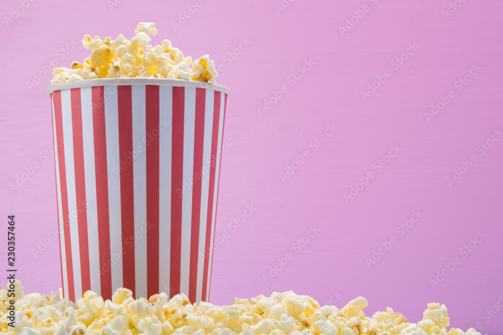 a bucket of popcorn stands on cereal, on a pink background, on the right there is a place to write