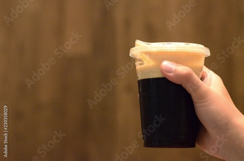 Quadro su tela The hand holding a cup of cold nitro black coffee using a sip cup that no need to use straw for environment friendly