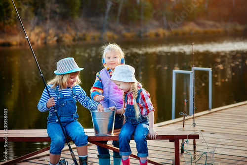 Three young children brag about fish caught on the bait. Concept of friendship and fun weekend or vacation