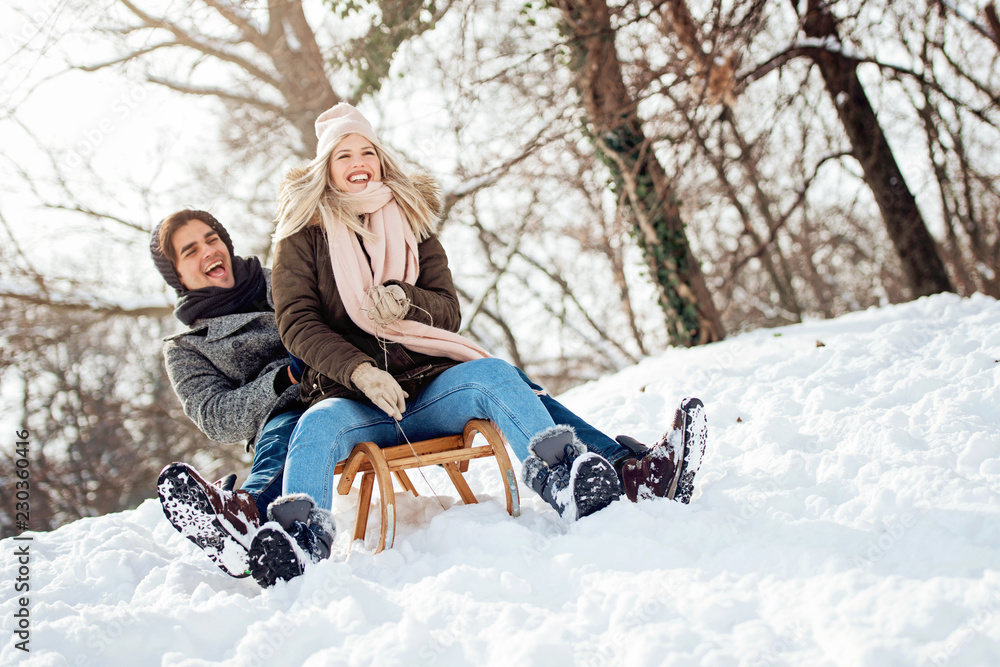 Two young people sliding on a sled  - obrazy, fototapety, plakaty 