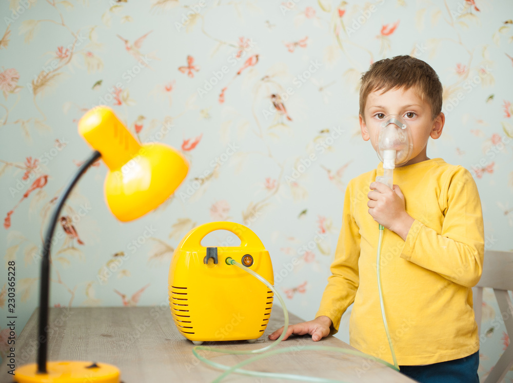 Fototapeta premium cute little caucasian boy making inhalation at home using electric medical gear