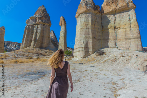 backview of women in brown dress in love valley in Turkey, Cappadocia with blue sky and sand hills in background