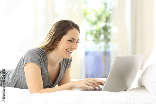 Happy lady using a laptop on the bed at home © Antonioguillem