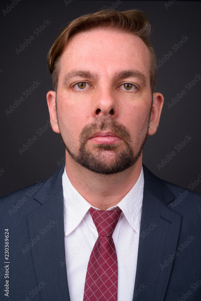 Blond bearded businessman with goatee against gray background Blond bearded businessman with goatee against gray background
