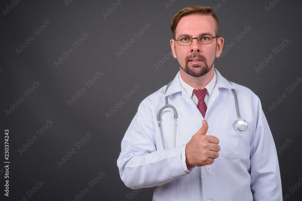 Blond bearded man doctor with goatee against gray background Blond bearded man doctor with goatee against gray background