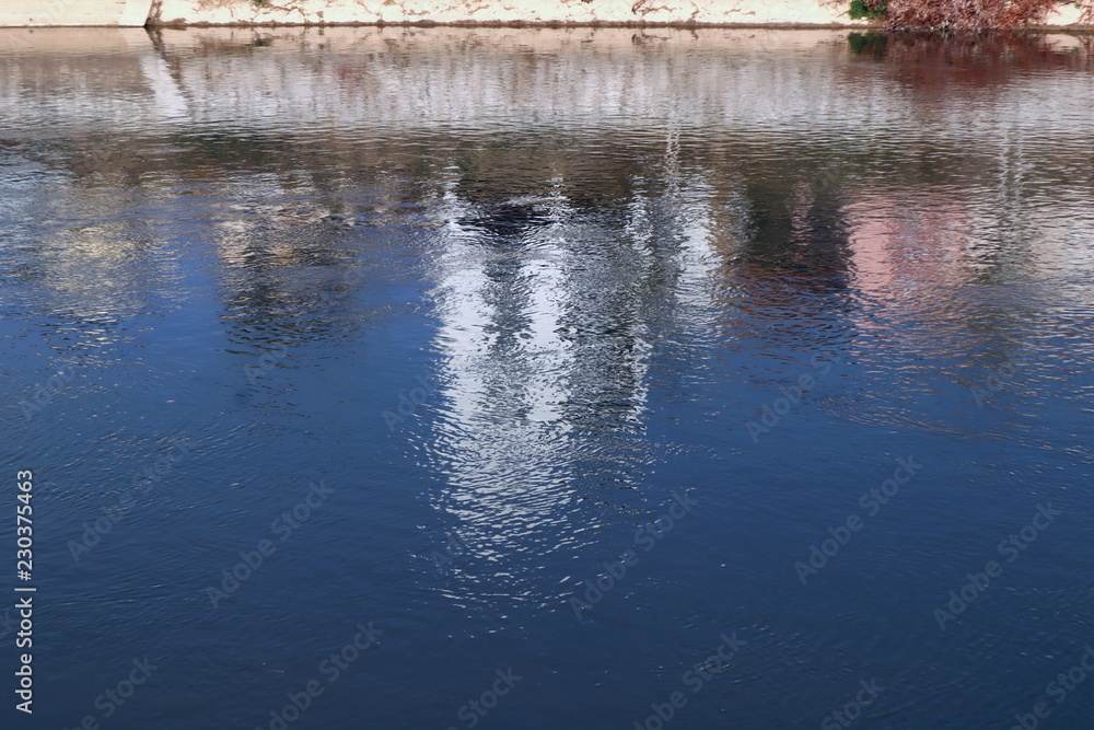 Fototapeta premium background or wallpaper of water,reflecton of blue sky and white building in river on sunny day, copy space water texture