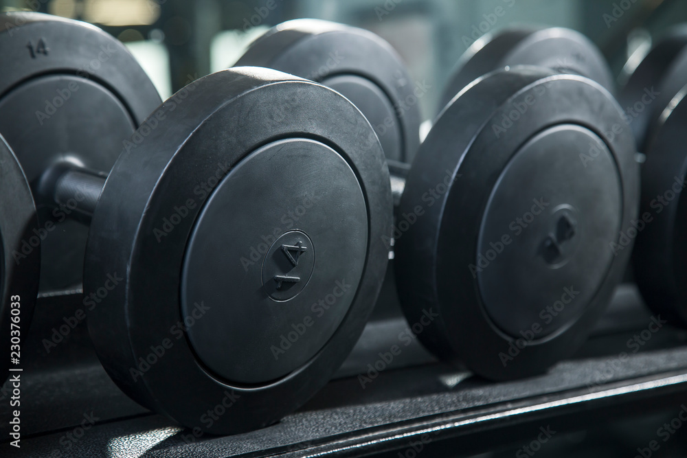 Black metal dumbbell set. Close up many metal dumbbells on rack in gym Black metal dumbbell set. Close up many metal dumbbells on rack in gym