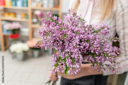Sunny spring morning. Young happy woman holding a beautiful bunch of lilac. Present for a smiles girl.