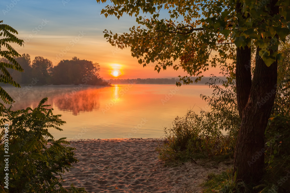 Sunrise over the river with trees on foreground at autumn Sunrise over the river with trees on foreground at autumn