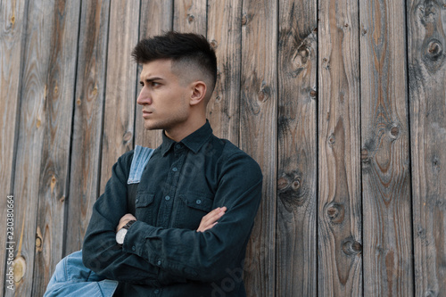 A Young stylish model man posing on wood background with a backp photo