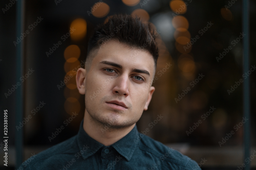 Young handsome man close up portrait with lights in background