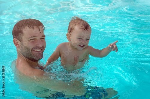 Father and child are having fun in pool. Dad and son are swimming indoor pool. Father teachs son to swim. Concept of kids sport, family summer vacation. Concept of healthy holiday and family activity.