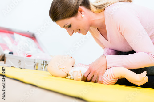 Woman in first aid course practicing revival of infant on baby doll photo