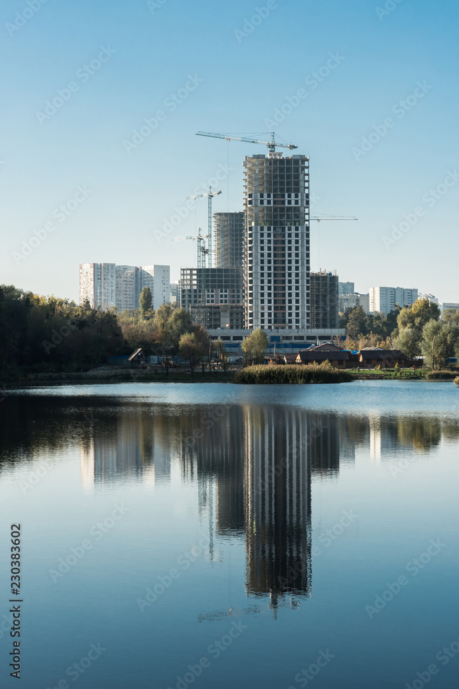 modern buildings with reflection in lake in city in autumn