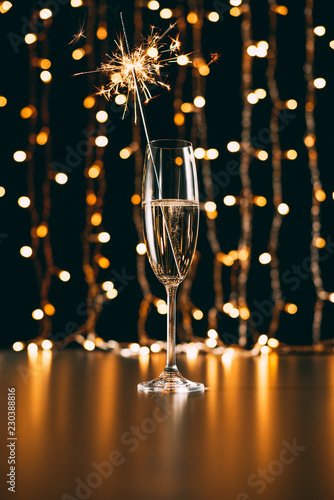 Champagne with Christmas sparkle on garland light background