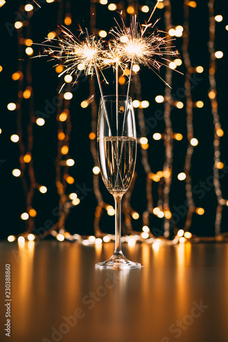 Champagne with Christmas sparkles on garland light background