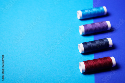 Red and blue sewing threads on double-colored background.