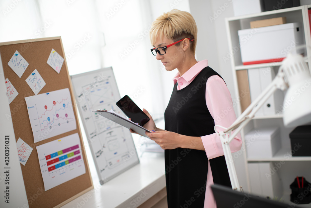 A young girl standing in the office and holding a phone. A young girl standing in the office and holding a phone.