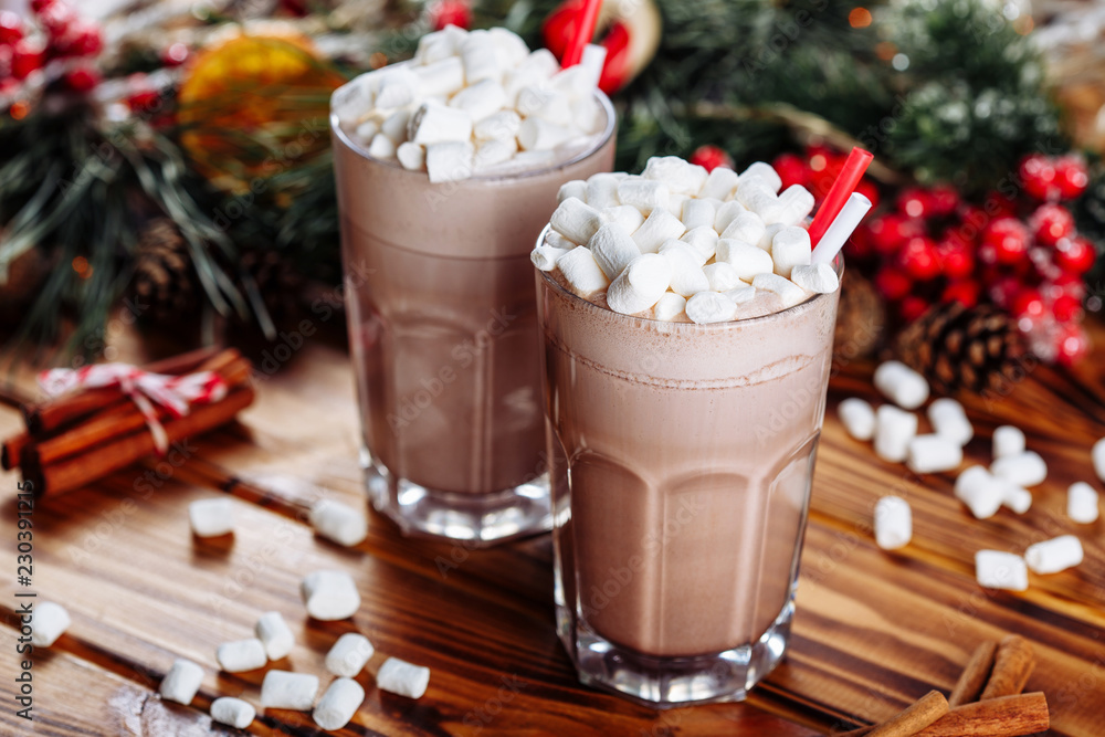 Homemade two Cocoa glasses with Marshmallows. Hot winter drink on wooden Backdrop decorated with cinamon sticks and fir branches Homemade two Cocoa glasses with Marshmallows. Hot winter drink on wooden Backdrop decorated with cinamon sticks and fir branches