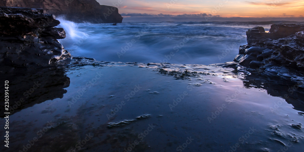 Sea water crashing on rocks in San Diego at sunset