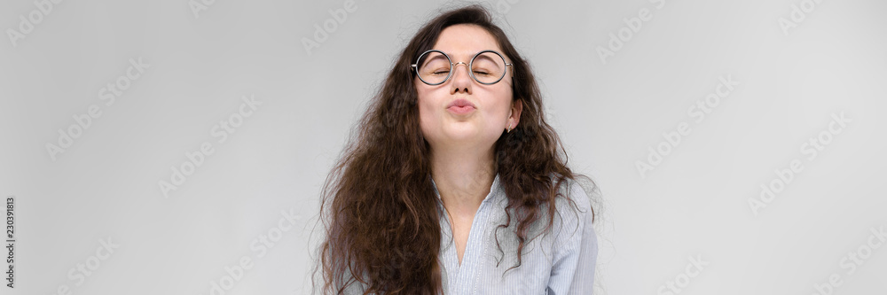 Obraz premium Young brunette girl with glasses. The girl pulls her lips for a kiss. The girl closed her eyes.