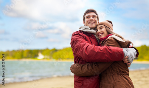 love, relationships and people concept - happy teenage couple hugging over autumn beach background