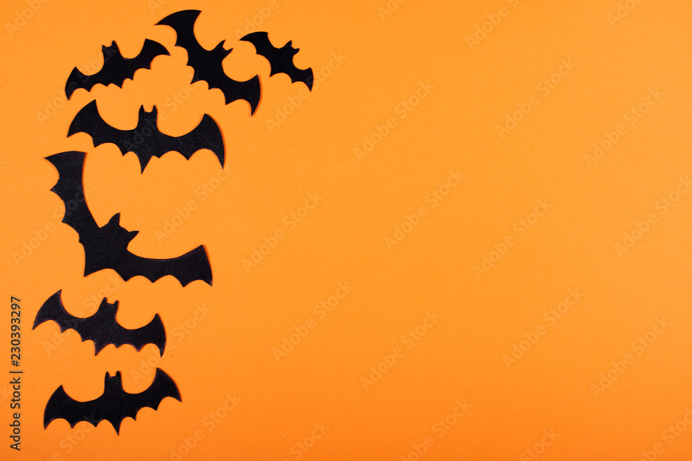 Flock of paper bats on orange wall.