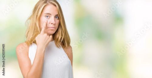 Beautiful young elegant woman over isolated background Pointing to the eye watching you gesture, suspicious expression