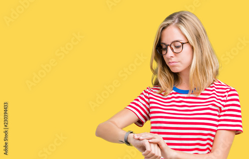 Beautiful young woman wearing glasses over isolated background Checking the time on wrist watch  relaxed and confident