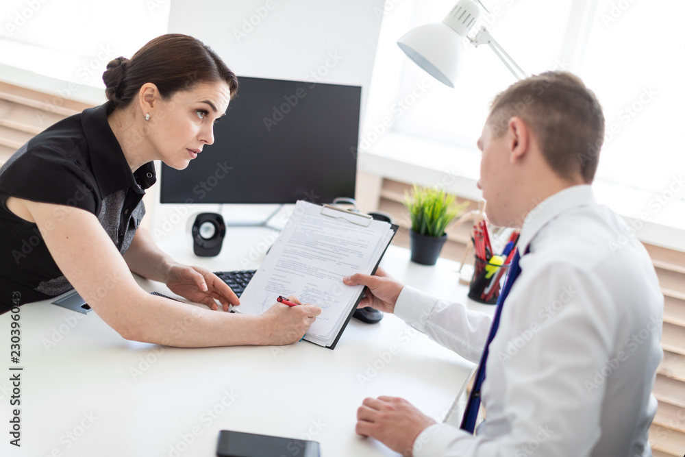 Fototapeta premium Young people sit in the office at the computer table and work with documents.