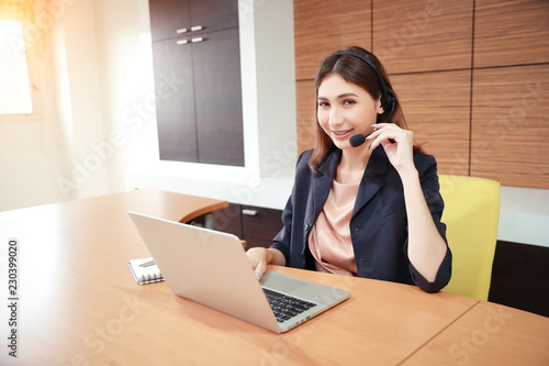 portrait of beautiful call center woman with headphones and computer